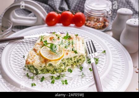 Vegetarian lasagna with spinach and microgreens on a white plate. Tasty and healthy food. Stock Photo