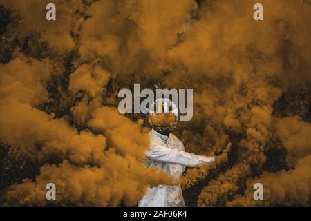 guy in mask standing in between orange brown smoke bombs Stock Photo