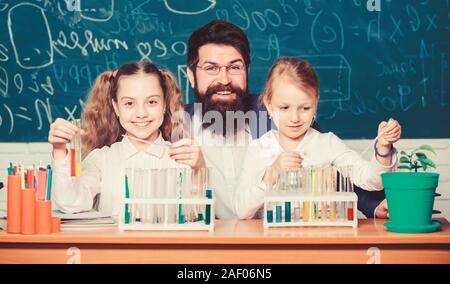 Man bearded teacher work with microscope and test tubes in biology classroom. School biology experiment. Explaining biology to children. How to interest children study. Fascinating biology lesson. Stock Photo