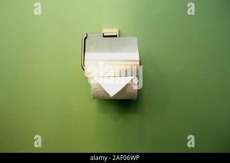 Close-up of toilet roll holder in bathroom near green wall Stock Photo