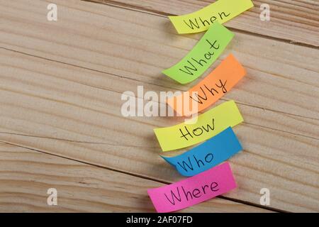 Questions - Why? What? Where? When? Why? How? on colorful stickers on wooden desk Stock Photo
