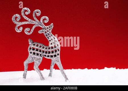 Silver beautiful glitter deer walking on the snow cover on red holiday and anf festive background with copy space for text. Marry Christmas and Happy Stock Photo