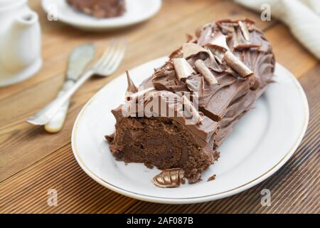 Chocolate swiss roll isolated on a wooden background. Chocolate sweet dessert. Pastry for breakfast or tea. Stock Photo