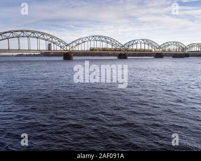 A train is crossing the Daugav River heading to Riga Central Station on a cold day in March 2018 Stock Photo