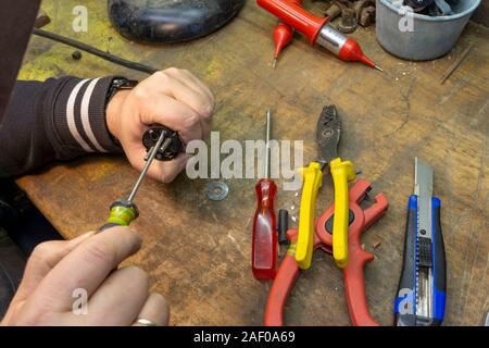 Electrician repairs a cable, there are tools on his workbench. Stock Photo