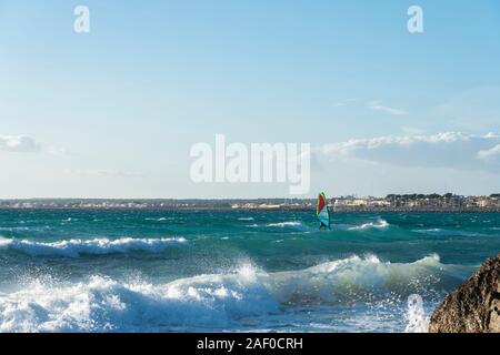 Ses Covetes / Colonia de San Jordi, Campos, Majorca, Spain - December 09, 2019: Seascape with waves and a man enjoying and practicing windsurfing Stock Photo