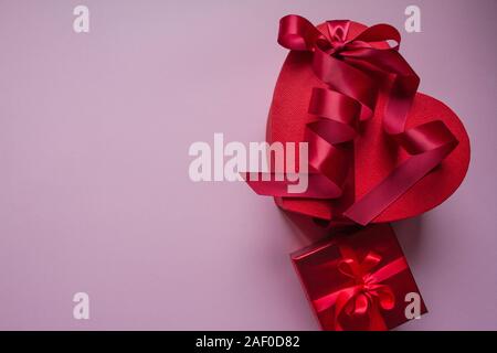 Several red gift boxes of different shapes with red ribbon on a pink background, gift concept Stock Photo