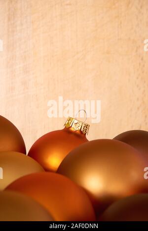 Mat bronze orange colored chtristmas balls in front of a woorden background for use as a christmas card template with copy space. Vertical image Stock Photo