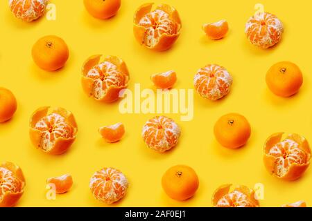 Mandarin pattern on a yellow or orange background, New Year and Christmas concept, peeled tangerines and peeled, mandarin slice. Flat lay Stock Photo