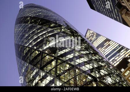 Windows of the gherkin skyscraper building and high rise office buildings lit up at night in the City of London England UK   KATHY DEWITT Stock Photo