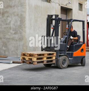worker on loader transports pallets Stock Photo