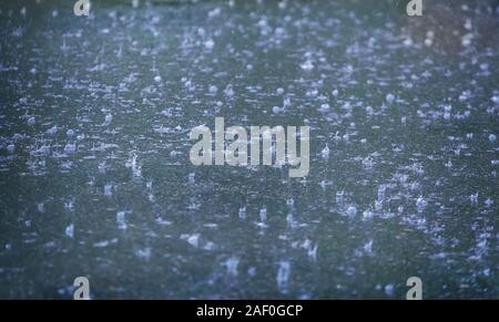 rain drops falling in pool on asphalt Stock Photo