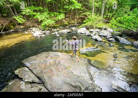 Young boy playing by river in the woods Stock Photo