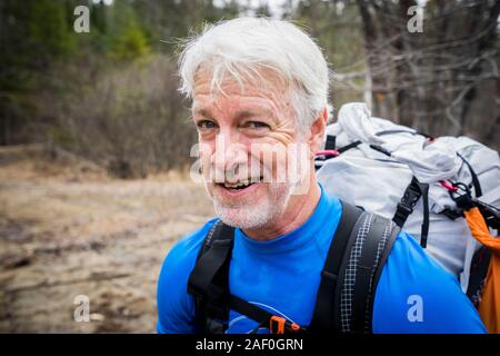 Older man smirking with a backpack on Stock Photo