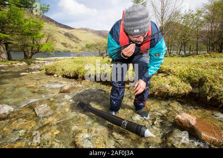 Dr Jeff Warburton of Durham university empties a sediment trap from a river entering Buttermere Lake in the Lake District National Park as part of a s Stock Photo