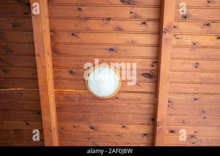 White round lamp on a wooden ceiling in an loft Stock Photo