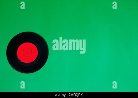 Vinyl record on a green background. Retro style. Top view. Stock Photo