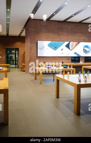 Strasbourg, France - Dec 24, 2018: View rom the street of Apple Computers Store with empty hall and multiple devices working on wooden tables latest iPhone XS and HomePod and Apple Watch Stock Photo