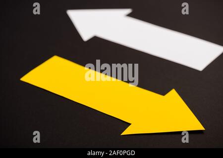 selective focus of yellow directional arrow isolated on black Stock Photo