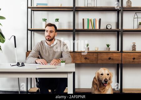 Blind man reading at table and golden retriever sitting beside Stock Photo