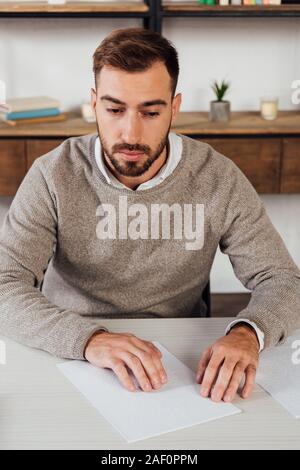 Blind man reading paper with braille font at table Stock Photo