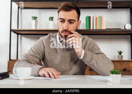 Pensive blind man reading at table beside coffee cup Stock Photo