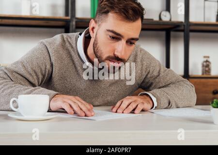 Blind man reading braille font beside coffee at table Stock Photo