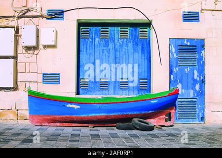 Classic blue color of the year 2020 in traditional color schemes of colorful Malta. Traditional fisherman boat on the pavement in front of the boat do Stock Photo