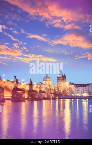 Charles Bridge reflected in Vltava river in Prague on a sunset. Vertical image with neon color toning with golden, yellow, orange, purple, violet and