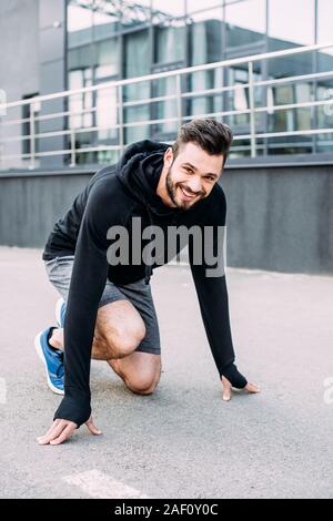smiling handsome sportsman in starting position ready to run Stock Photo