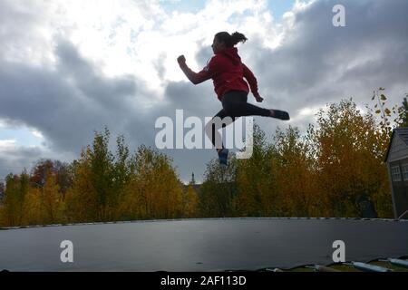 Teenage girl doing acrobatics on trampoline Stock Photo