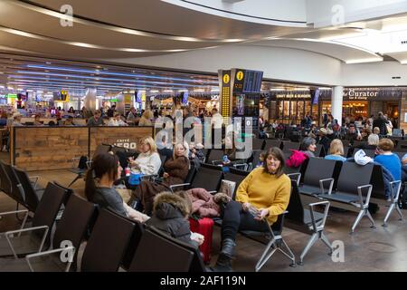 Heathrow airport London UK; terminal 3 interior; passengers sitting waiting for their flights, Heathrow London UK Stock Photo