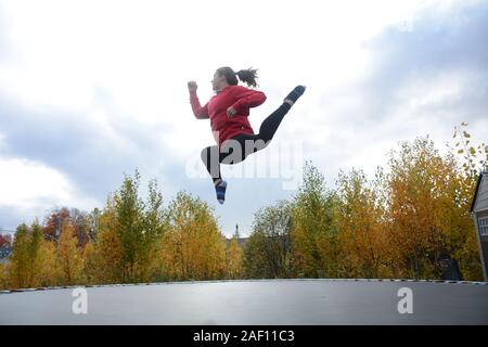 Teenage girl doing acrobatics on trampoline Stock Photo