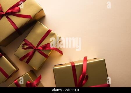 top view of golden gift boxes with red ribbons and bows on beige background Stock Photo
