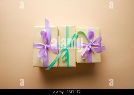 top view of gift boxes with violet and green ribbons on beige background Stock Photo
