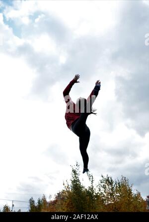 Teenage girl doing acrobatics on trampoline Stock Photo