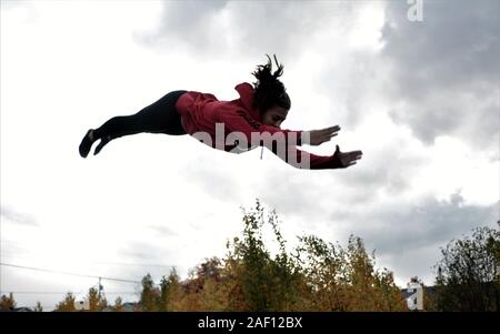 Teenage girl doing acrobatics on trampoline Stock Photo