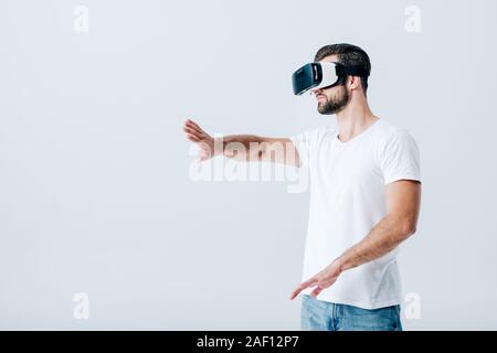 bearded man in Virtual reality headset gesturing isolated on grey Stock Photo