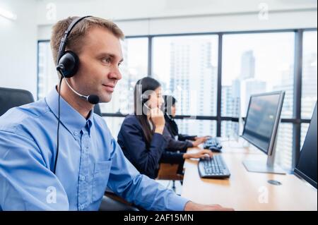 Group of young profession call center operator agent with headsets working in office. Business telemarketing service people concentrating on having co Stock Photo