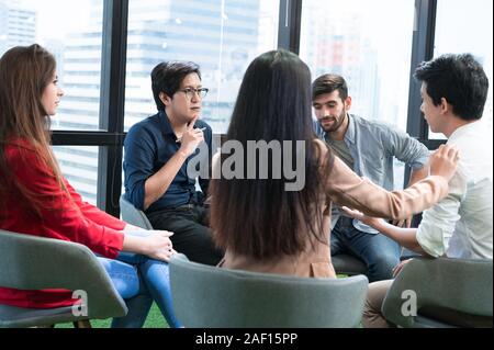 Psychotherapist inquiring about symptoms occurring within mind from patients with mental health problems in hospital. Group psychotherapy for support Stock Photo