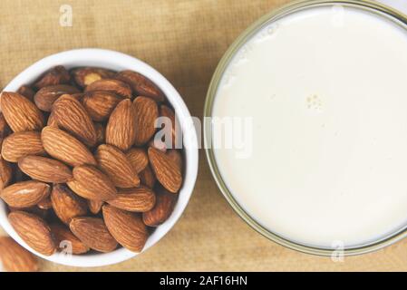 Almond milk in bowl and almonds nuts on sack background Stock Photo