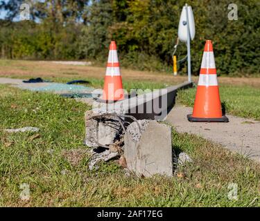 Concrete streetlight pole broken from car accident with exposed wires and laying across sidewalk. orange traffic cones, shattered glass in background Stock Photo