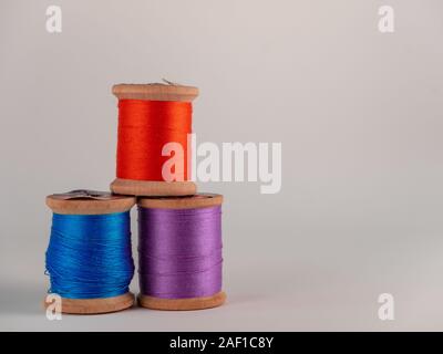 Three  antique wooden spools of sewing thread with bright colored thread Stock Photo