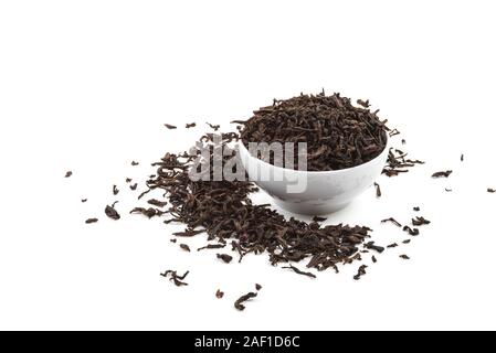 Dried tea leaves in ceramic cup over white background Stock Photo