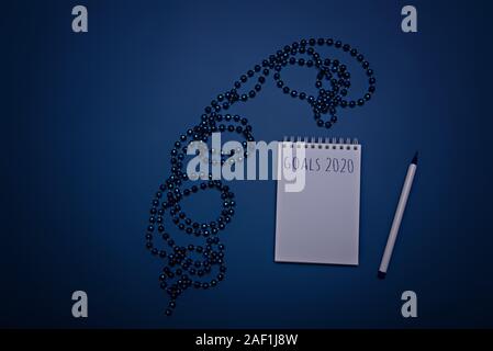 Blue Christmas beads, notebook and pen on a blue background. Color of the year 2020, Classic Blue Stock Photo