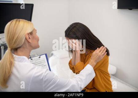 Blond doctor in white robe telling the test results to patient Stock Photo