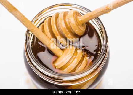 jar with honey and wooden honey dippers isolated on white Stock Photo