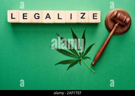 top view of green cannabis leaf, legalize lettering on wooden blocks and gavel on green background Stock Photo