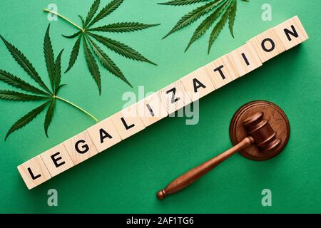 top view of green cannabis leaves and legalization word on wooden blocks near gavel on green background Stock Photo