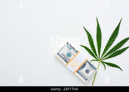 top view of medical cannabis leaf near dollar banknotes on white background Stock Photo